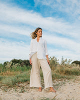 Girl standing on the beach wearing a white linen button down shirt